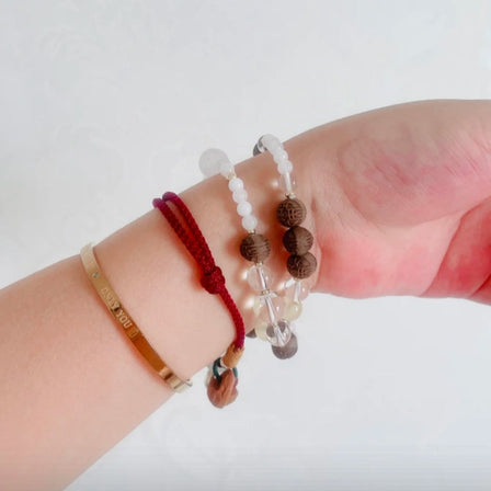 Crystal bracelet for energy with magnolia-infused beads on natural stone background with sunlight