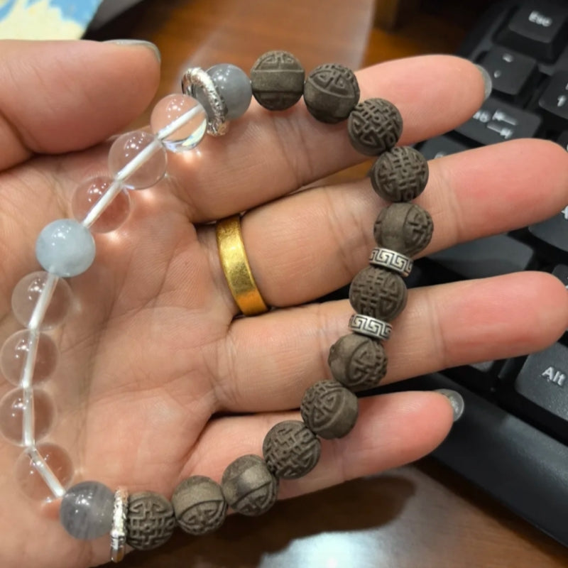 Magnolia Serenity Bracelet by Laxne Kongyulan featuring herbal-infused crystal beads in a hand display.